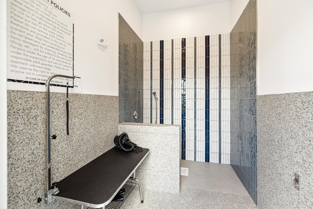 a large tiled shower with a black bench in a public restroom