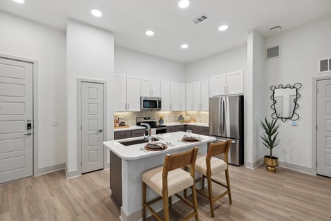 A kitchen with a table and chairs in front of it.