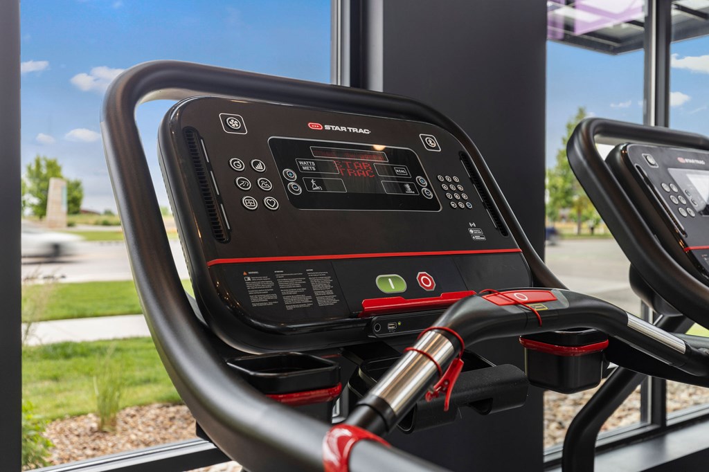 A close up of a black and red exercise bike with a digital display.