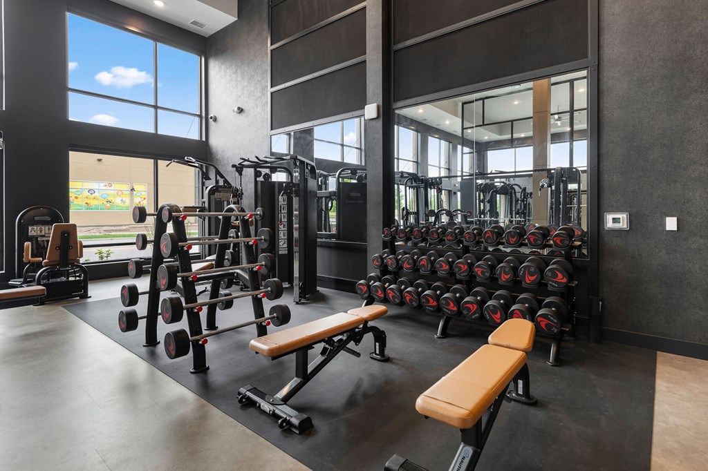 A gym with a variety of equipment including dumbbells, weight machines, and benches.