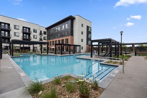 A swimming pool in front of a building with a black fence.