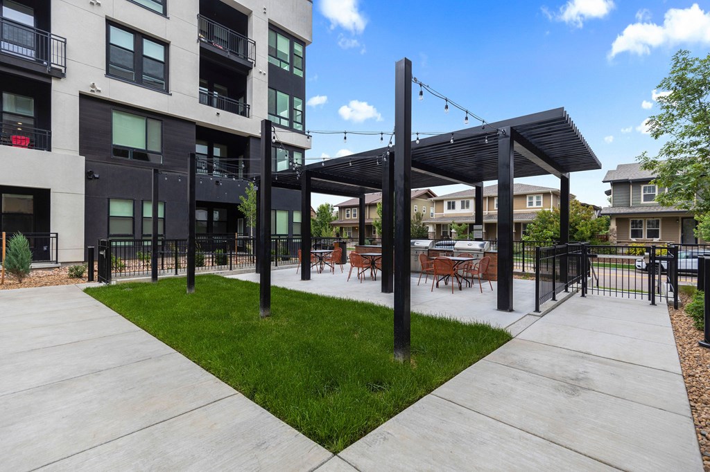 A patio area with a black pergola and chairs.