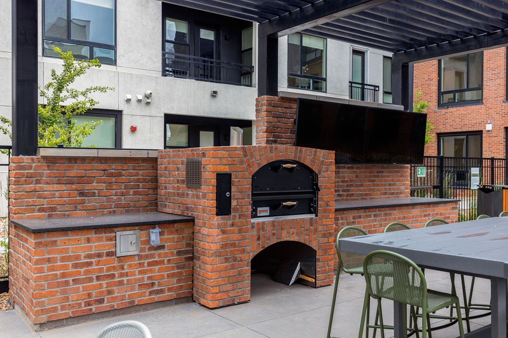 A brick oven is built into a wall on a patio.