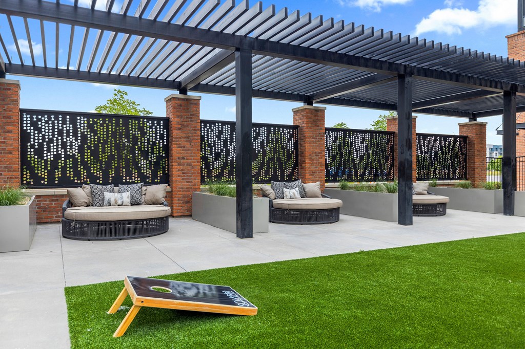A patio with a black and white striped awning, a brick wall with a black screen, and a black chalkboard on a stand.