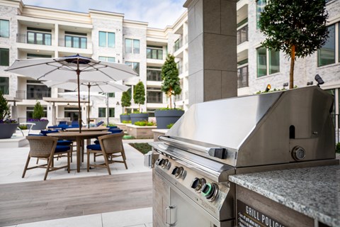 an outdoor kitchen with a grill and a table with chairs