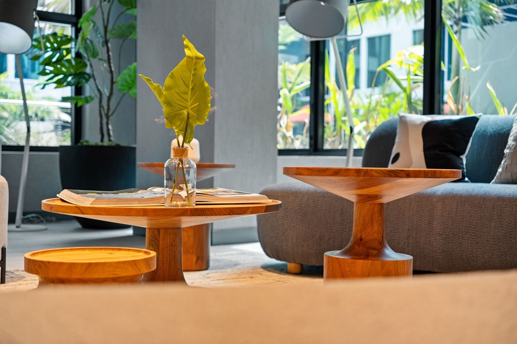 A yellow leaf in a vase sits on a wooden table.