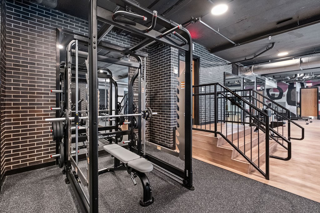 A gym with a bench, weights, and a railing.