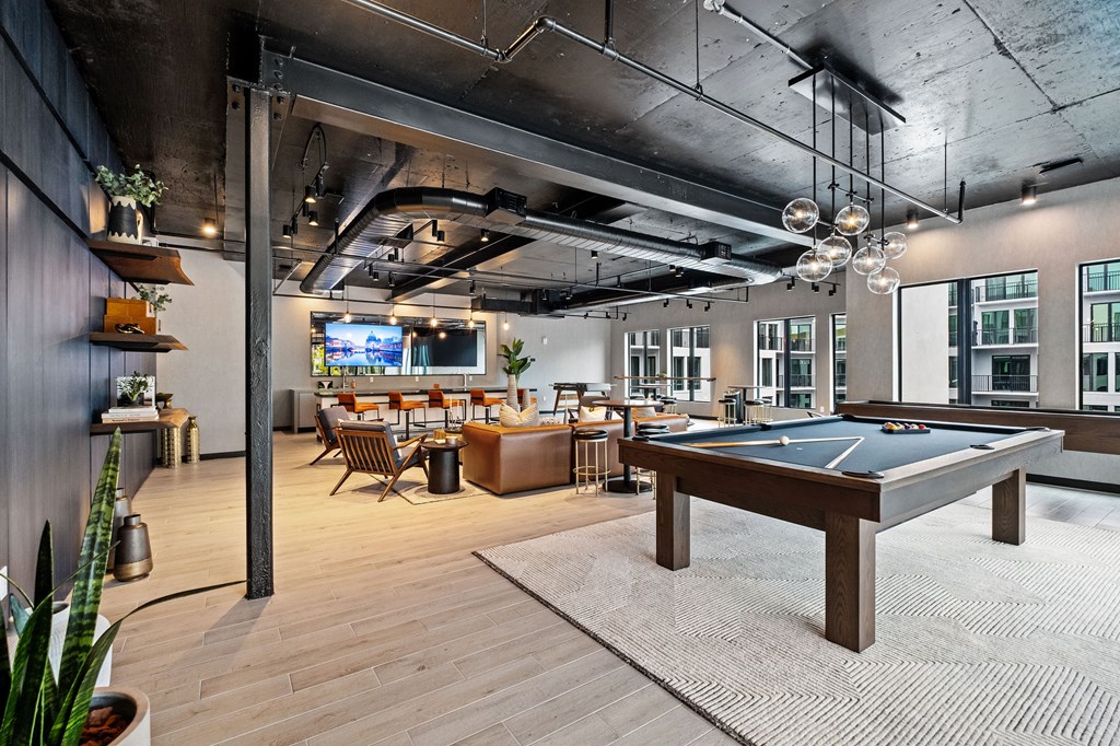 A room with a pool table and a bar area.