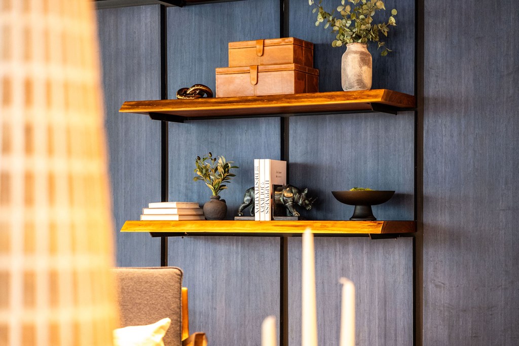 A shelf with various items including a plant, books, and a vase.