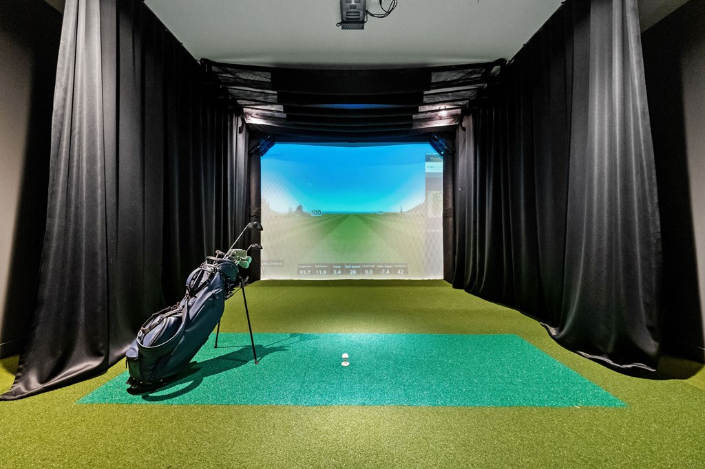 A room with a green carpet and a large screen on the wall.