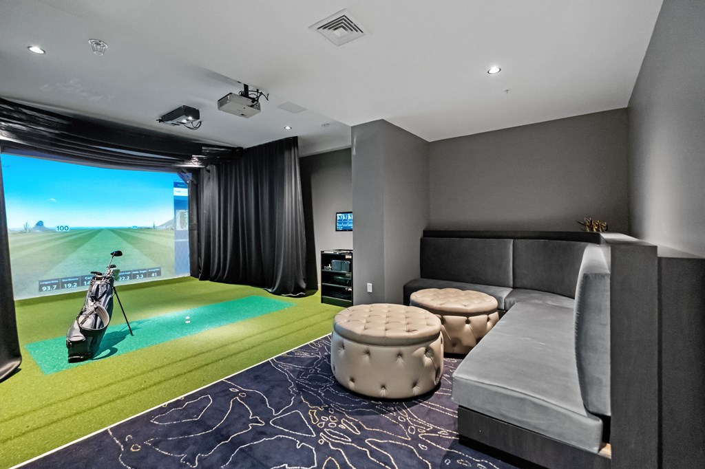 A room with a golf simulator and a couch.