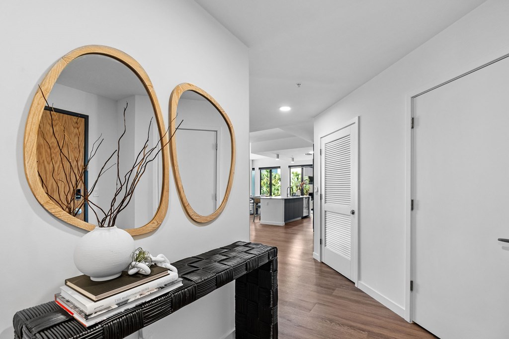 A hallway with a black bench and two round mirrors on the wall.