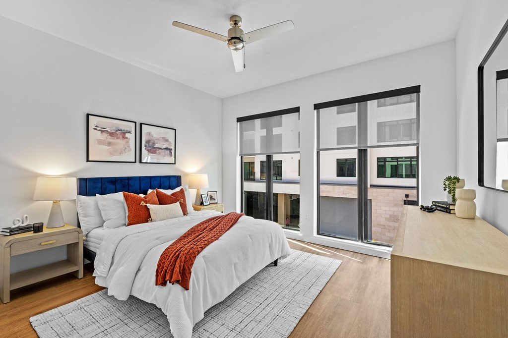 A bedroom with a bed, nightstand, and a ceiling fan.