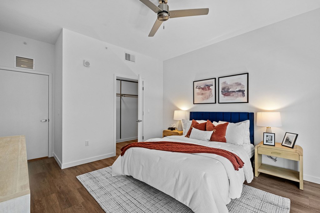 A bedroom with a bed, nightstand, and a ceiling fan.