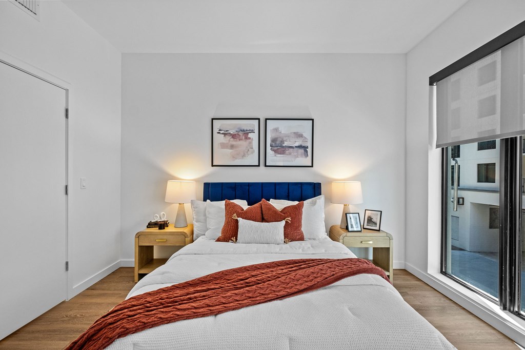 A bedroom with a large bed and two lamps.