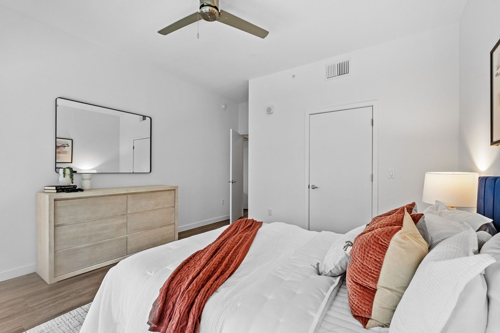 A bedroom with a bed, dresser, and mirror.