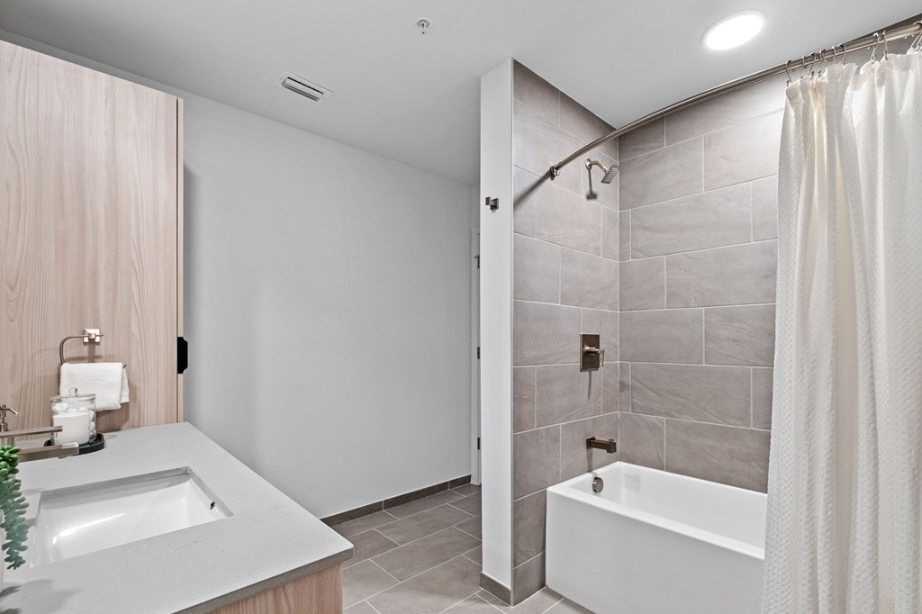 A modern bathroom with a white tub and a white sink.