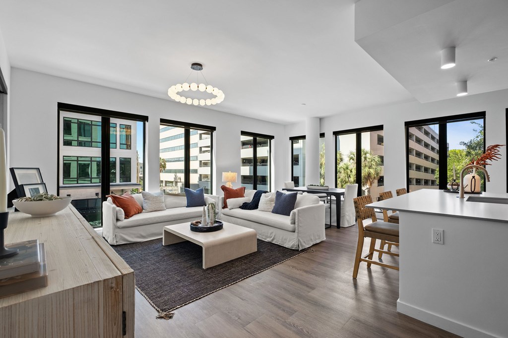 A modern living room with white furniture and a large window.
