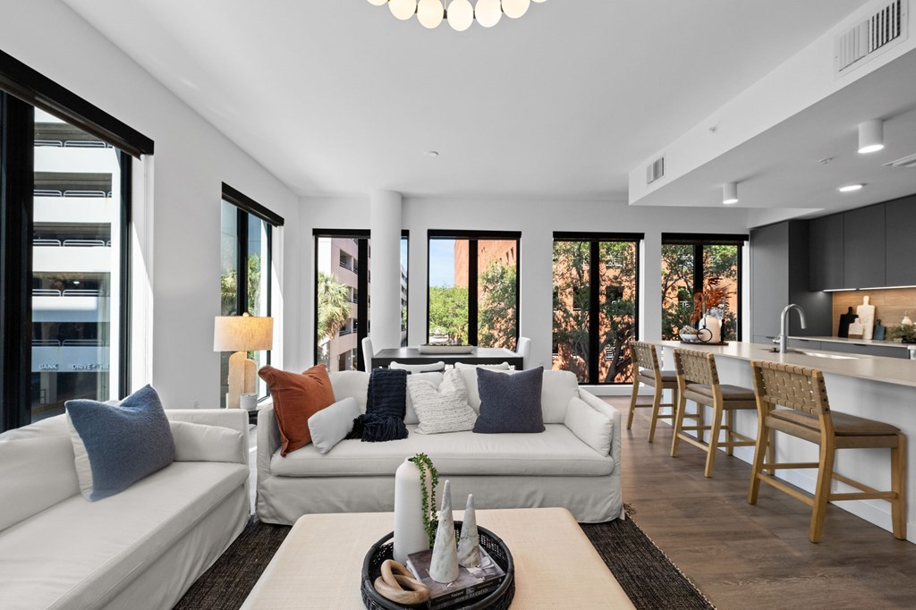 A modern living room with white furniture and a large window.