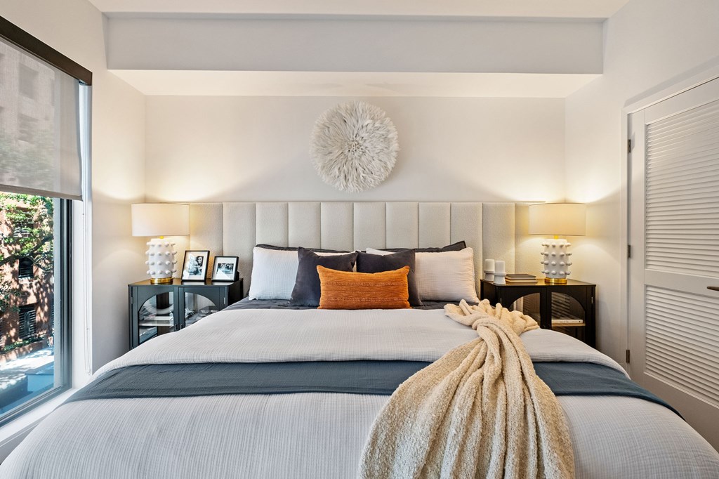 A bedroom with a large bed and a window overlooking a cityscape.