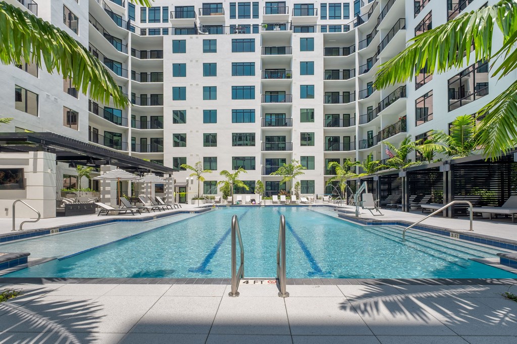 A large swimming pool in front of a tall white building.