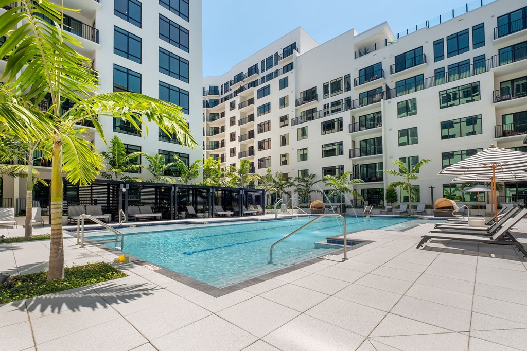 A swimming pool surrounded by palm trees and lounge chairs.