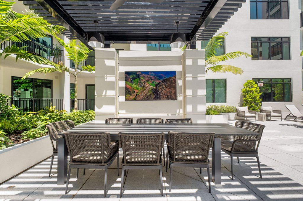 A patio with a table and chairs is surrounded by plants.