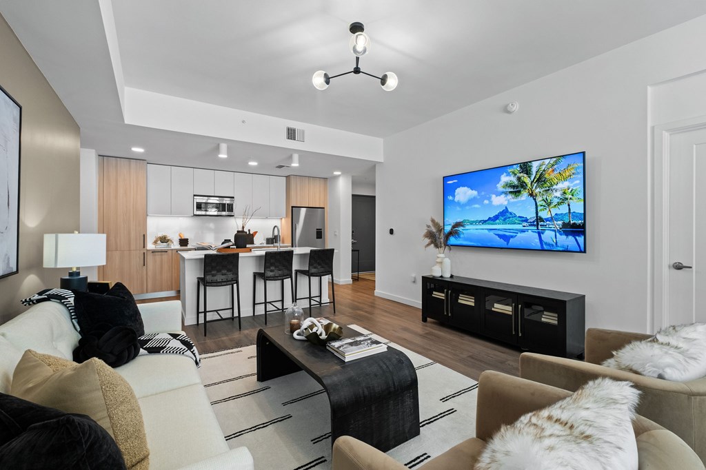 A modern living room with a bar area and a television displaying a tropical scene.