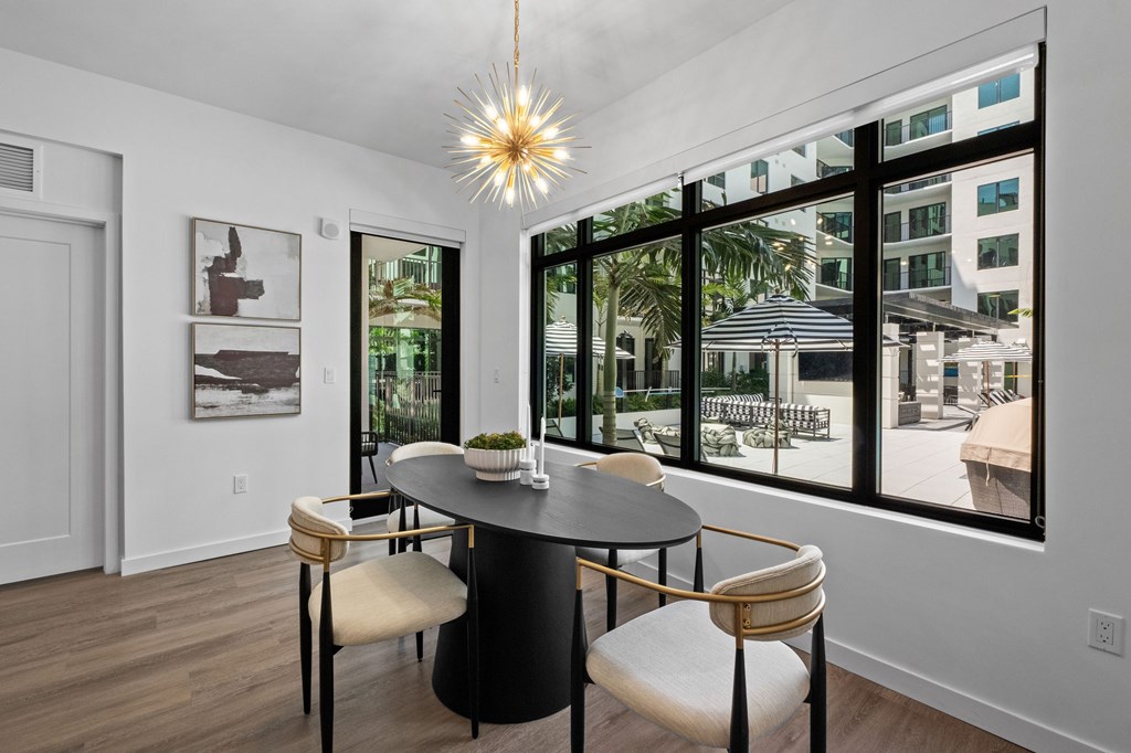 A dining room with a table and chairs and a view of the outside.