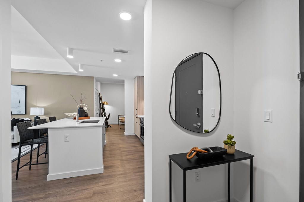 A modern kitchen with a white island and black chairs.