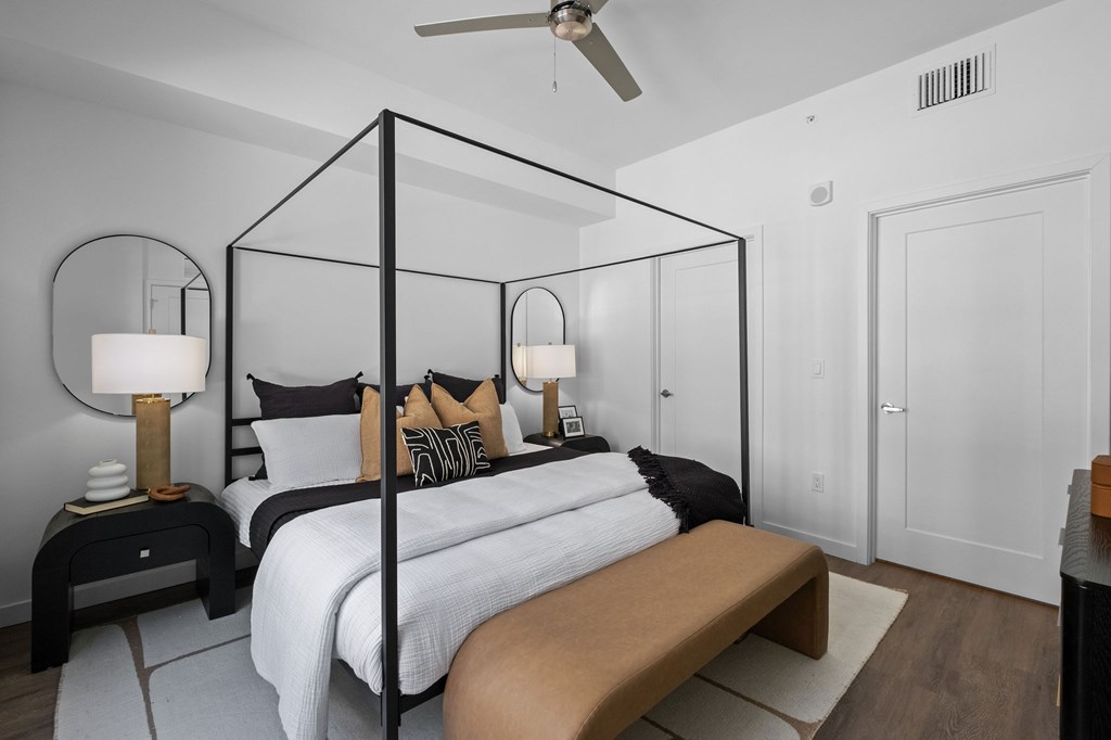 A modern bedroom with a four poster bed and a bench.