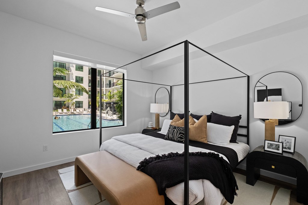 A modern bedroom with a four poster bed and a ceiling fan.