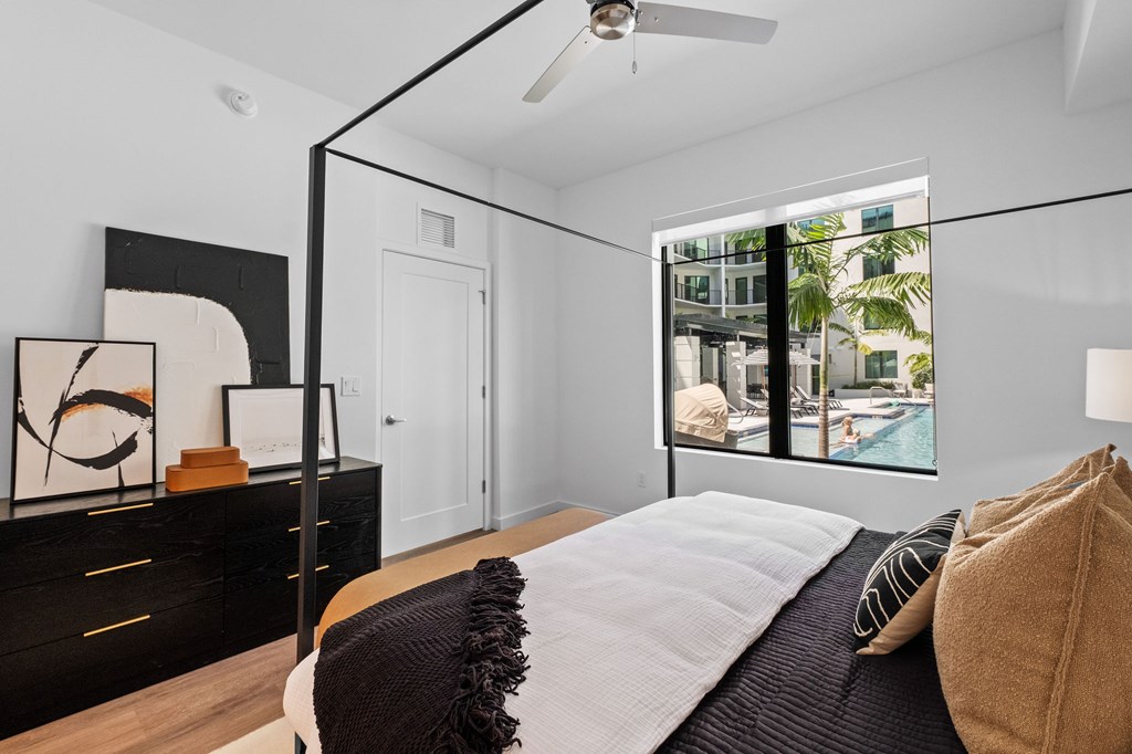 A bedroom with a bed, pillows, and a ceiling fan.