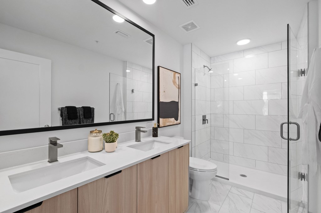 A modern bathroom with a large mirror above a double sink vanity.