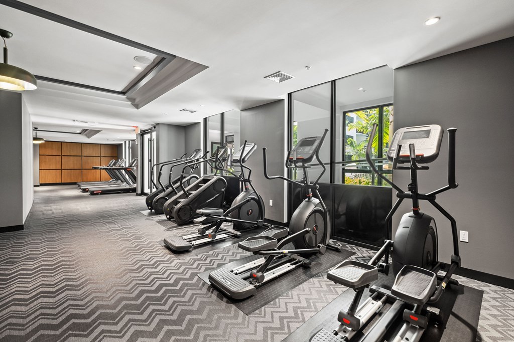 A gym with a variety of exercise equipment including treadmills, stationary bikes, and elliptical machines.