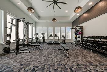 A spacious gym with a variety of equipment and a ceiling fan.