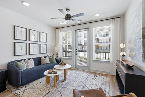 A living room with a blue couch, a coffee table, and a ceiling fan.