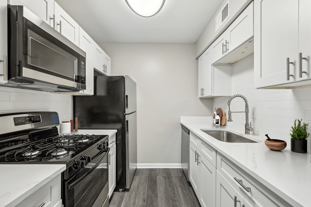 an empty kitchen with white cabinets and stainless steel appliances