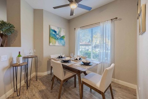 A dining room with a table set for four and a ceiling fan.