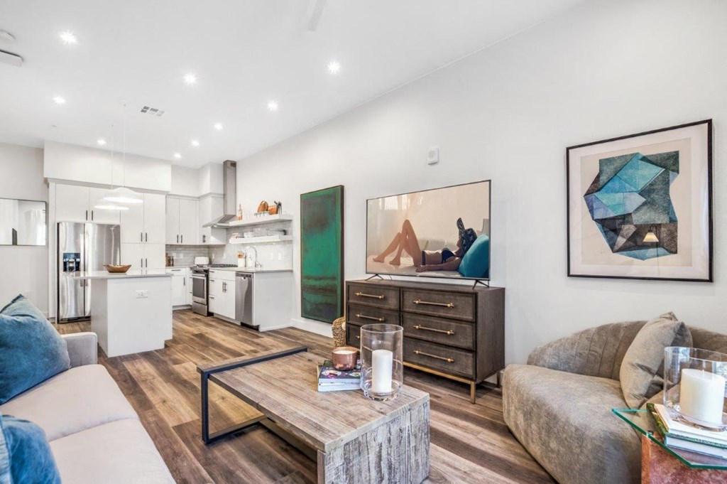 a living area with a couch coffee table and a kitchen in the background