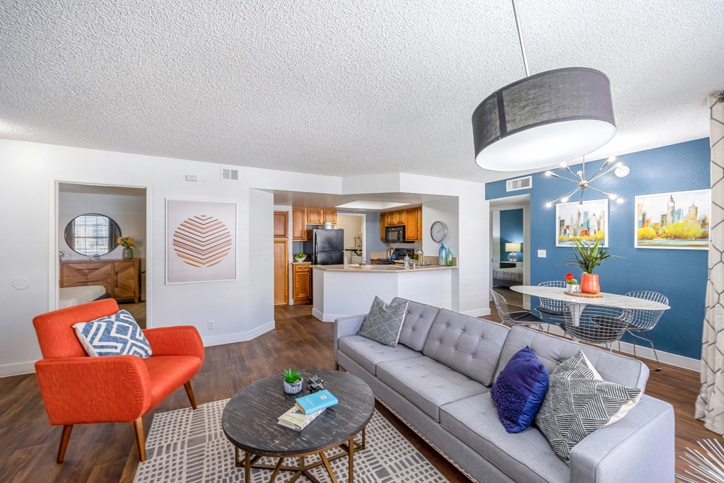 a living room with a couch table and chairs and a kitchen in the background