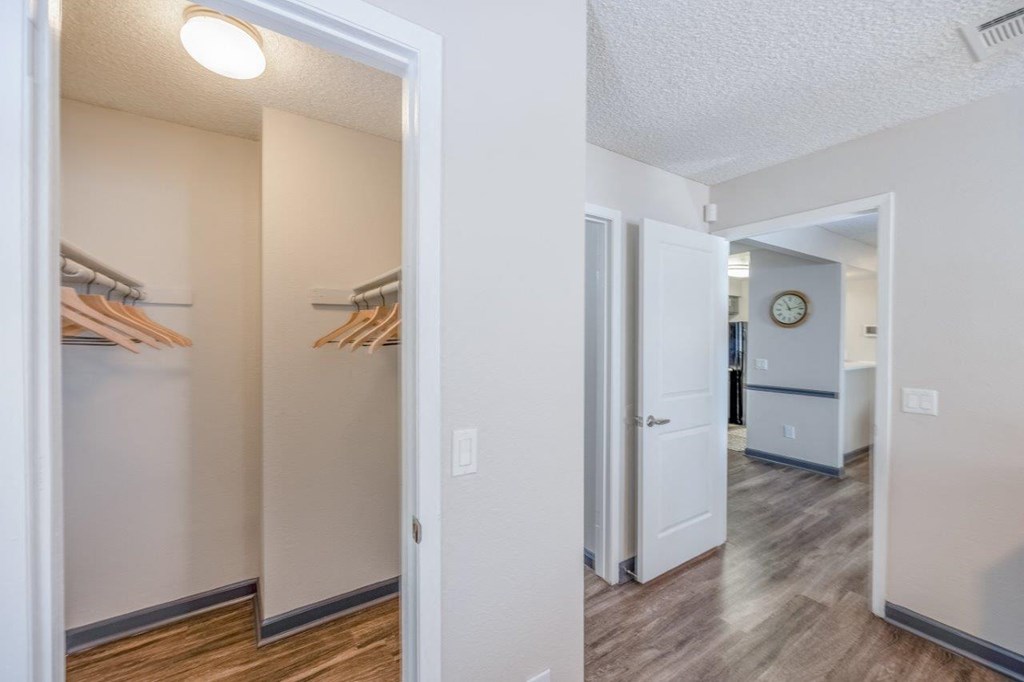 a hallway with a closet and a door to a room with a refrigerator