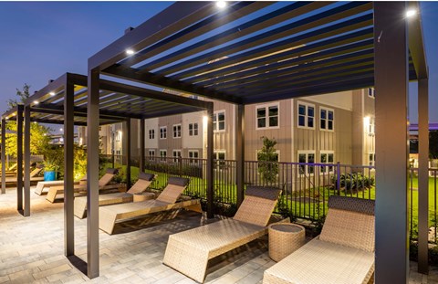 a patio with lounge chairs under awnings at night