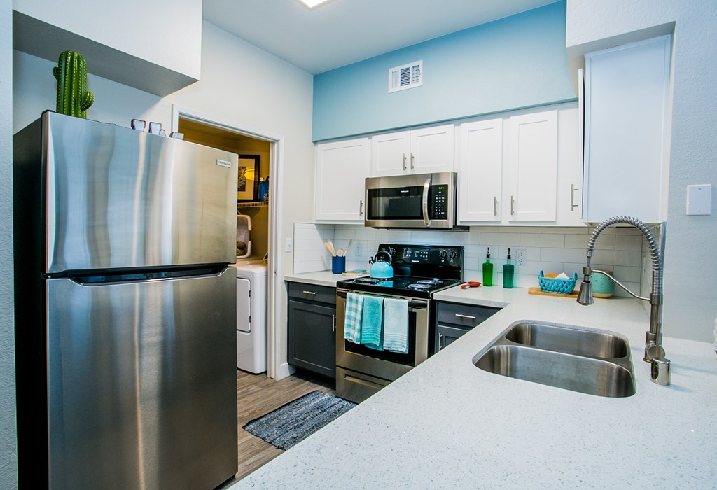 A kitchen with a stainless steel refrigerator and a sink.
