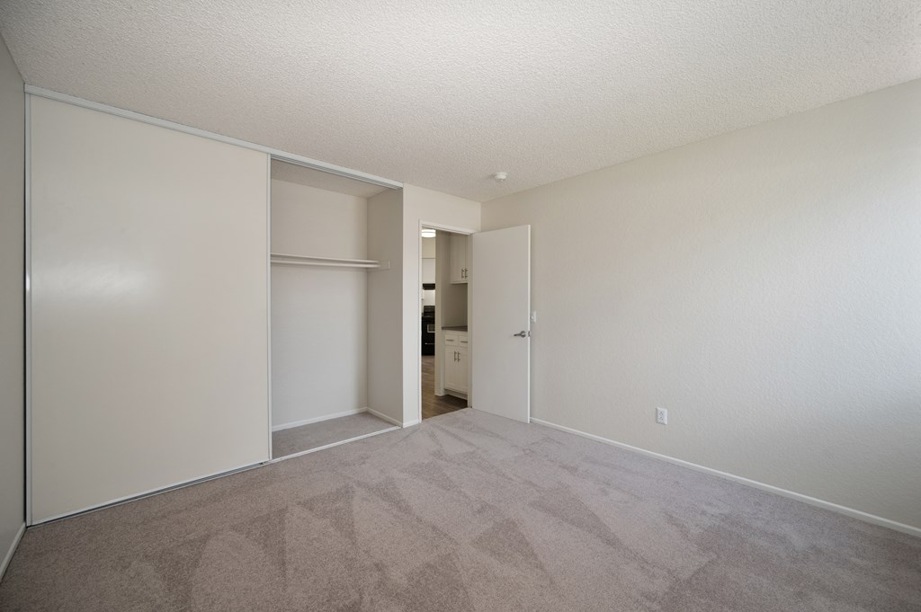 an empty bedroom with a door to a closet