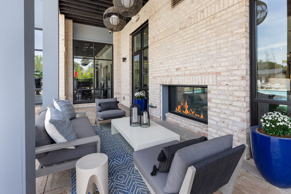 A modern patio with a fireplace and seating area.