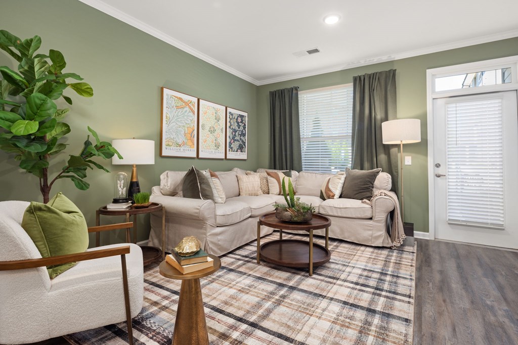 A living room with a white couch, a green pillow, and a wooden coffee table.