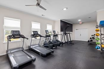 A spacious gym with treadmills, elliptical machines, and a fan.