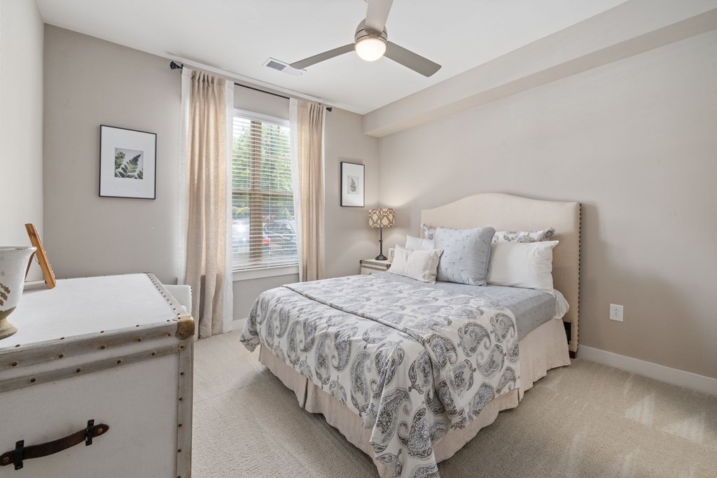 A bedroom with a bed, a dresser, and a ceiling fan.