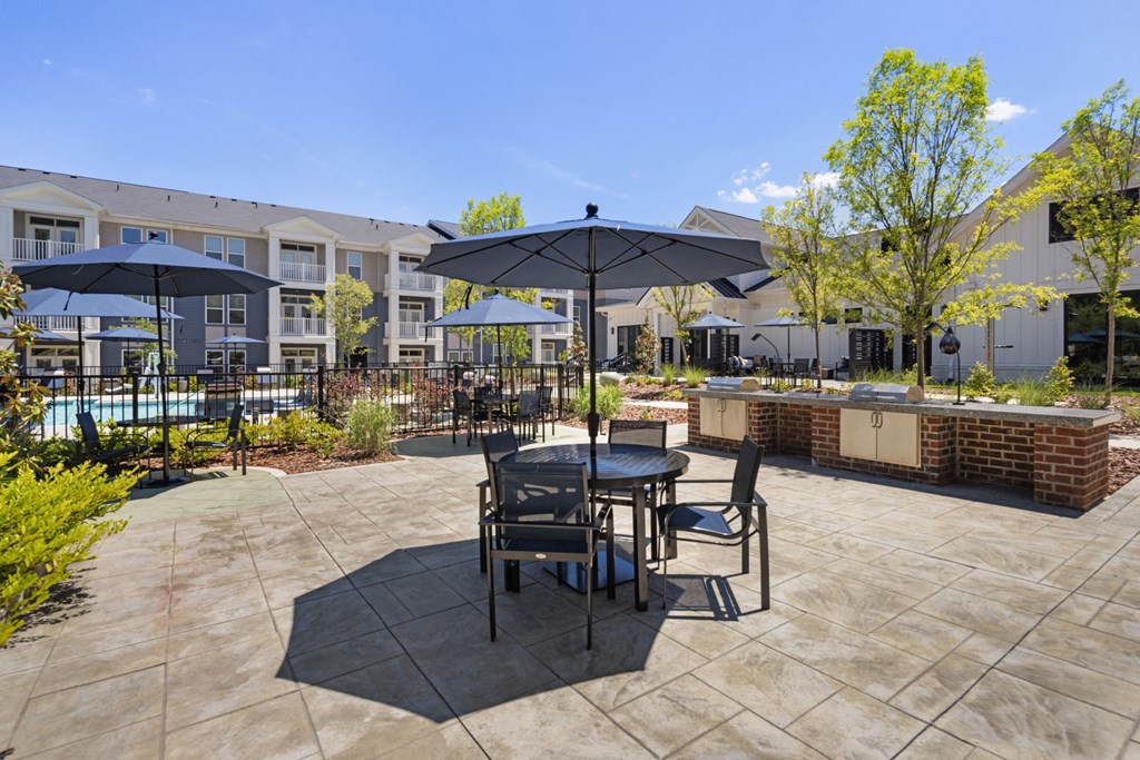 A patio with a table and chairs and umbrellas.